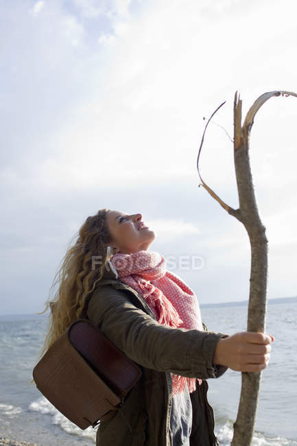 Woman by the sea with a large stick — Stock Photo