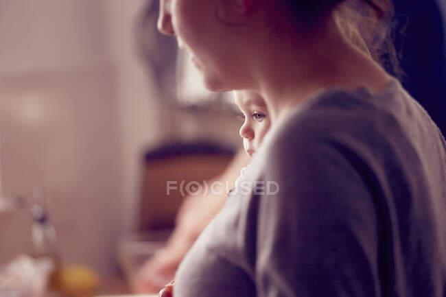 Mother carrying baby boy in kitchen — Stock Photo