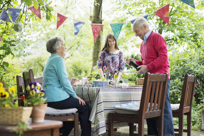 Family sitting down for outdoor meal in garden — Stock Photo