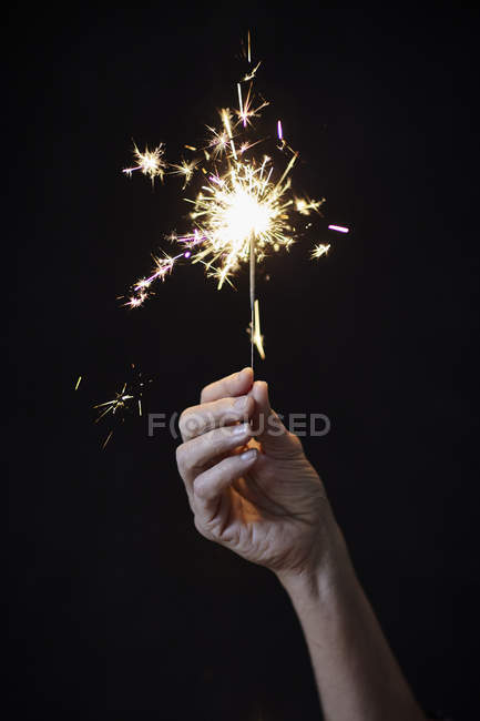 Cropped image of Woman's hand holding sparkler — Stock Photo