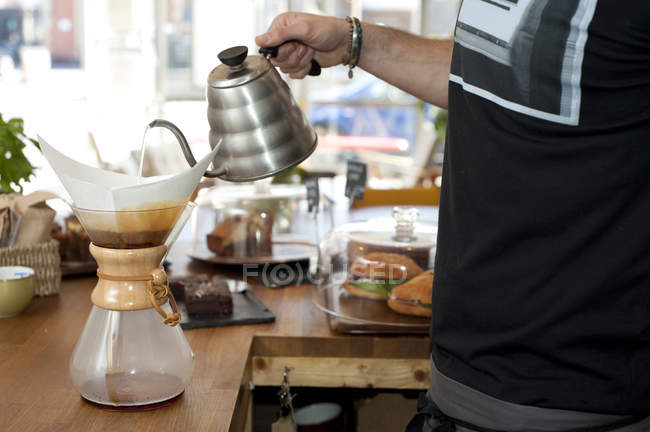 Mão de garçom café derramando água fervente em panela de café filtro — Fotografia de Stock