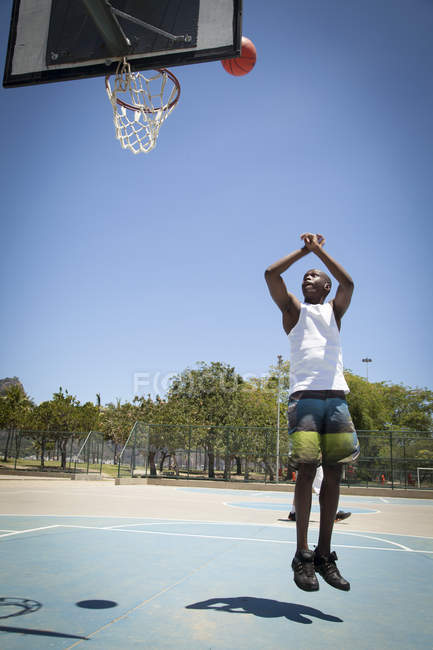 Male basketball player throwing ball toward basketball hoop — Stock Photo