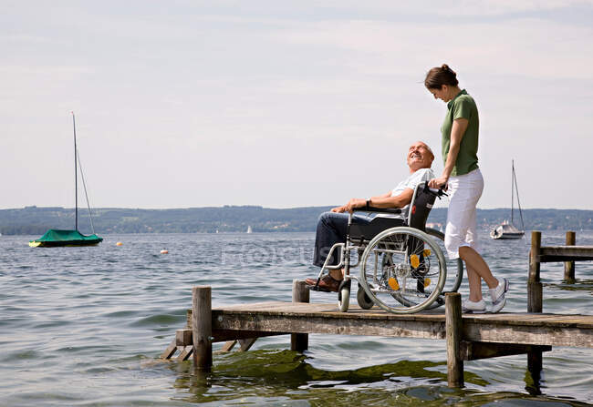 Женщина и старший мужчина в инвалидной коляске — стоковое фото