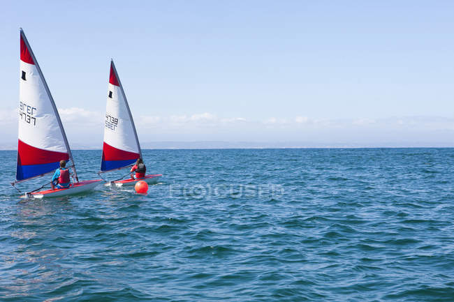 Teenagers riding sailing boats in open sea — Stock Photo