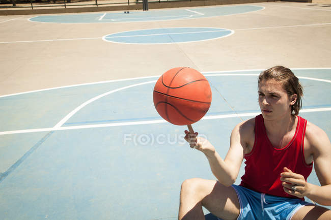 Giovane giocatore di basket maschile che gira palla sul dito — Foto stock