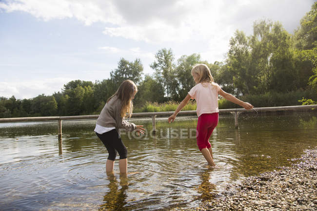 Two girls paddling in lake water — Stock Photo