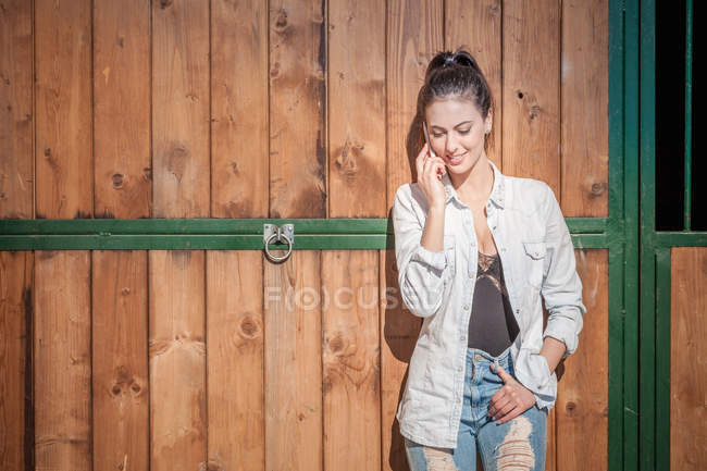Молода жінка на стайні на мобільний телефон — стокове фото