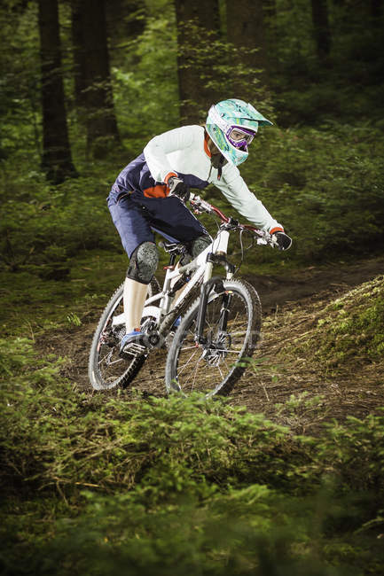 Young female downhill mountain biking in forest — Stock Photo