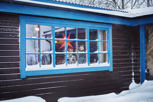 Zwei Brüder schauen zu Weihnachten aus dem verschneiten Kabinenfenster — Stockfoto