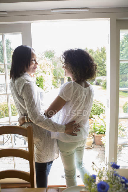 Мать и взрослая дочь, стоя у двери патио, разговаривая — стоковое фото