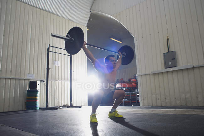 Взрослый мужчина поднимает штангу в спортзале — стоковое фото