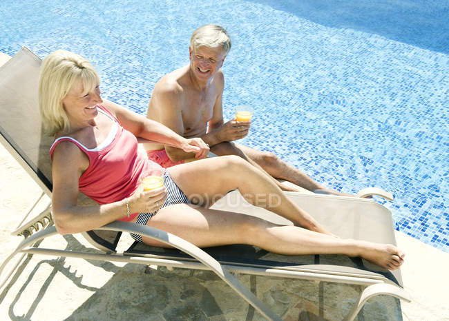 Зрелая пара разговаривает у бассейна — стоковое фото