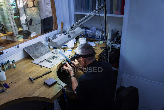 Jewelry craftsman filing platinum ring at workbench — Stock Photo