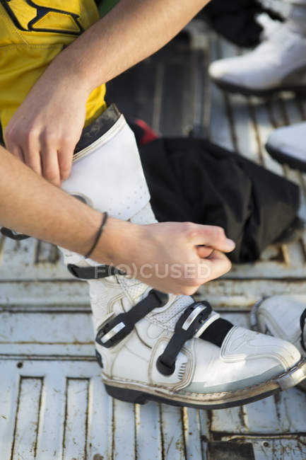 Close up of motocross motorcycle competitor fastening boot — Stock Photo