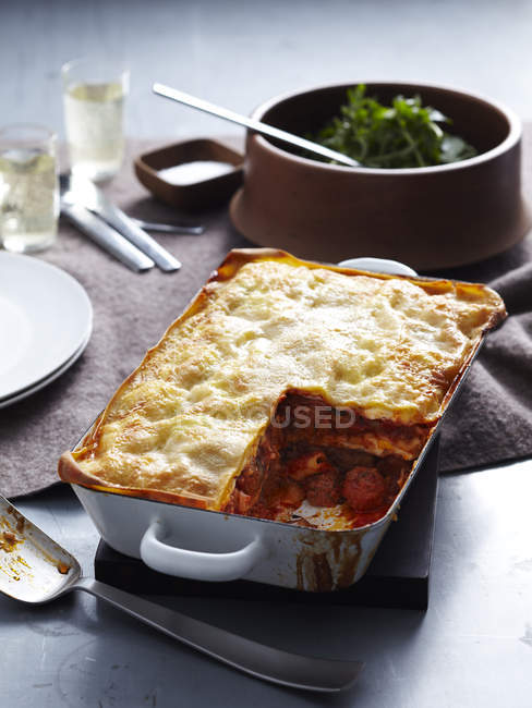 Fresh baked lasagne in dish with missing piece — Stock Photo