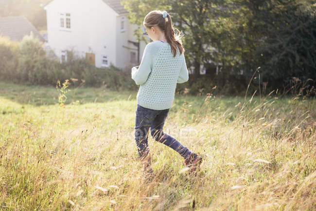 Girl walking through countryside garden — Stock Photo