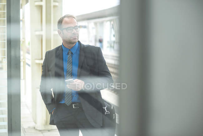 Бизнесмен в костюме держит мобильный телефон в руках — стоковое фото