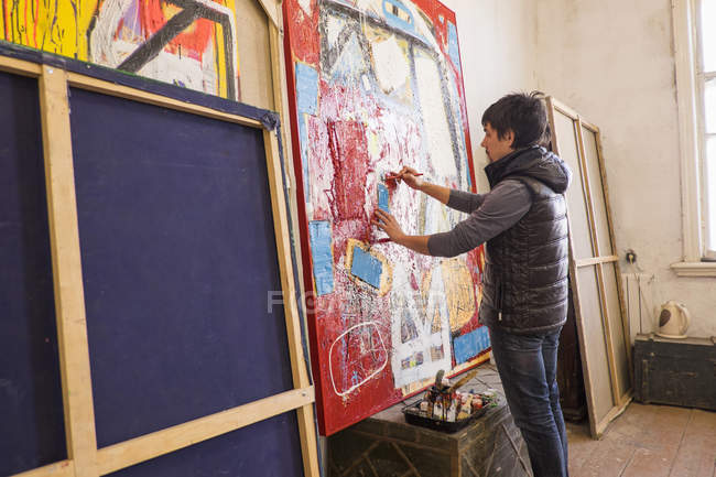 Artist drawing on abstract painting in studio — Stock Photo