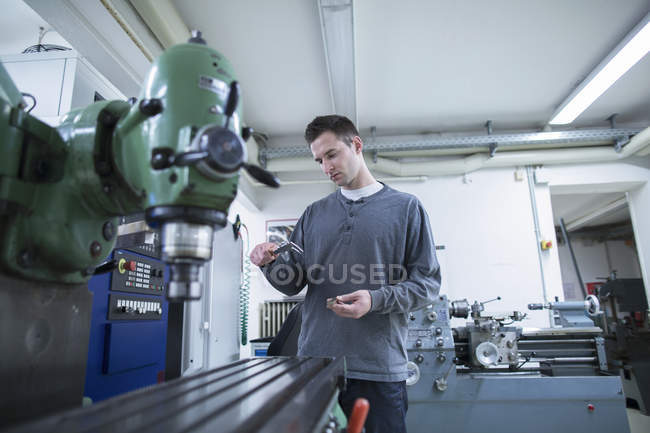 Young male technician using vernier caliper in workshop — Stock Photo