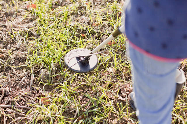 Cropped view of girl using metal detector in field — Stock Photo