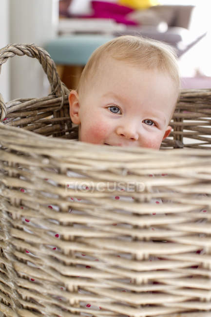 Porträt eines niedlichen weiblichen Kleinkindes, das sich im Weidenkorb versteckt — Stockfoto
