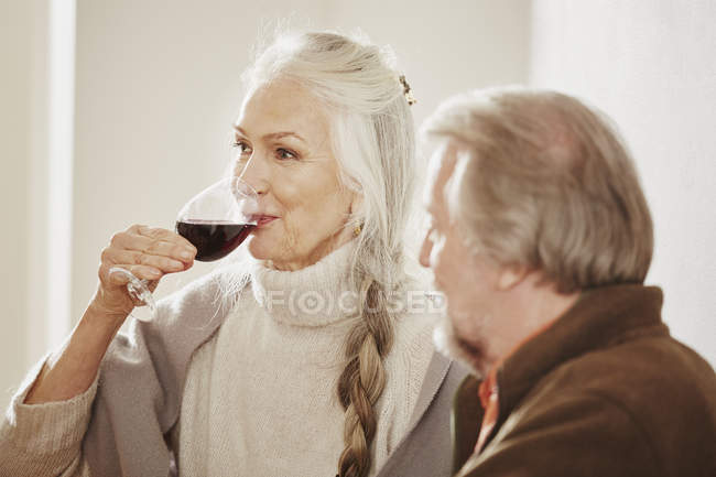 Mujer mayor bebiendo vino tinto - foto de stock