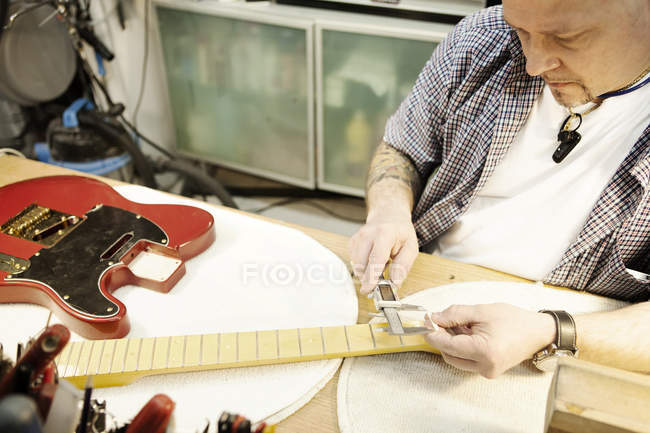 Gitarrenbauer überprüft Gitarrenhals in Werkstatt — Stockfoto