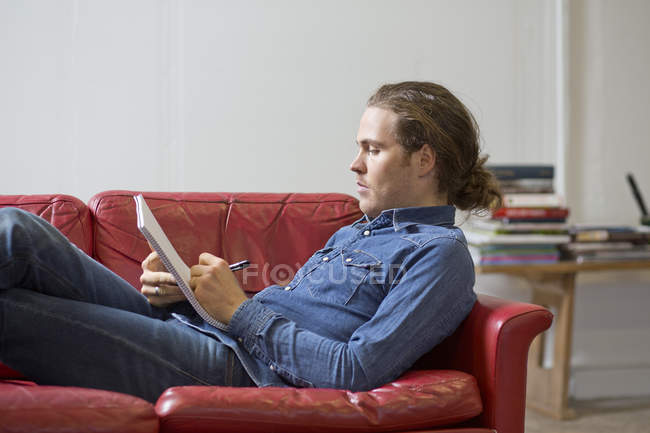 Man writing notes on couch — Stock Photo