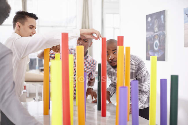 Colleagues in team building task balancing colourful tubes — Stock Photo