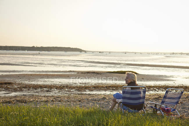 Senior mulher relaxante por praia — Fotografia de Stock