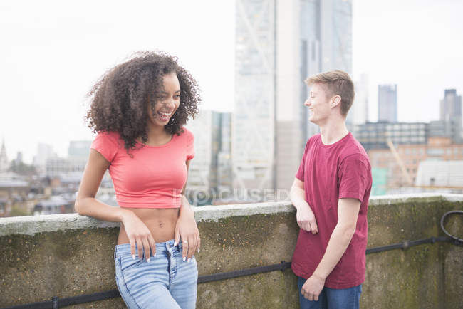 Young couple laughing by wall in city — Stock Photo
