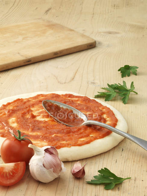 Prepared pizza base covered in tomato sauce — Stock Photo