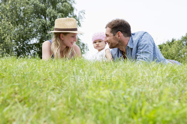 Mãe e pai com bebê filha na grama — Fotografia de Stock