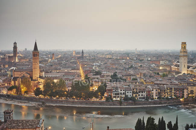 Vista elevada de los edificios de la ciudad de Verona iluminados al atardecer, Italia - foto de stock
