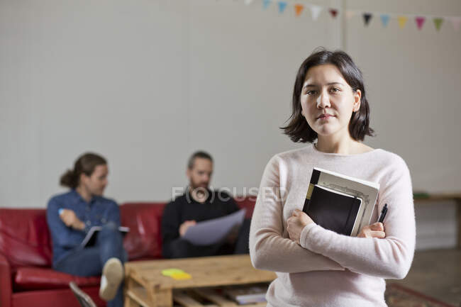 Donna con libri, colleghi in background — Foto stock