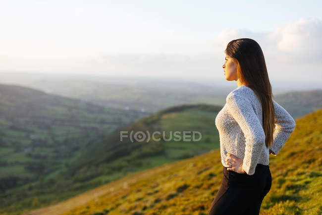 Vista trasera de la mujer joven con vistas al valle de Glyn Collwn, Brecon Beacons, Powys, Gales - foto de stock