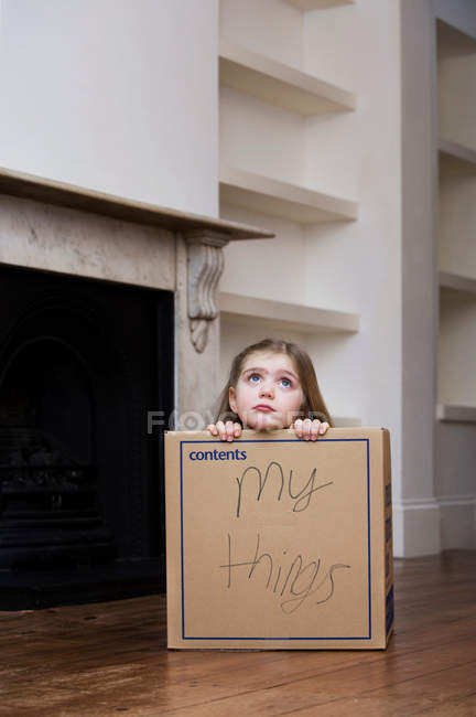 Ребенок сидит в коробке в доме — стоковое фото