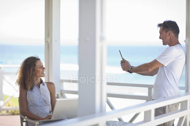 Pareja tomando fotografías en la playa casa balcón - foto de stock