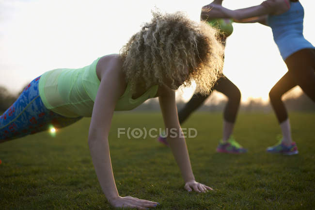 Retrato de la mujer haciendo ejercicio push up en el parque - foto de stock
