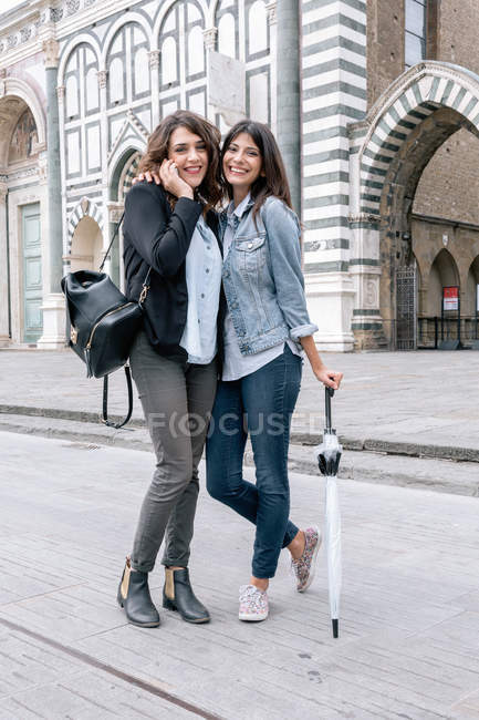 Coppia lesbica che parla al cellulare con l'ombrello in mano guardando la telecamera sorridente, Piazza Santa Maria Novella, Firenze, Toscana, Italia — Foto stock