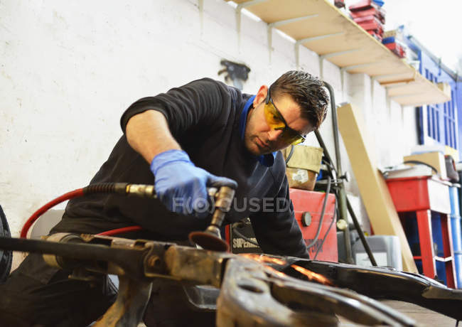 Mechanic cutting engine part with grinder — Stock Photo