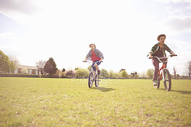 Boys cycling on playing field in London, UK — Stock Photo