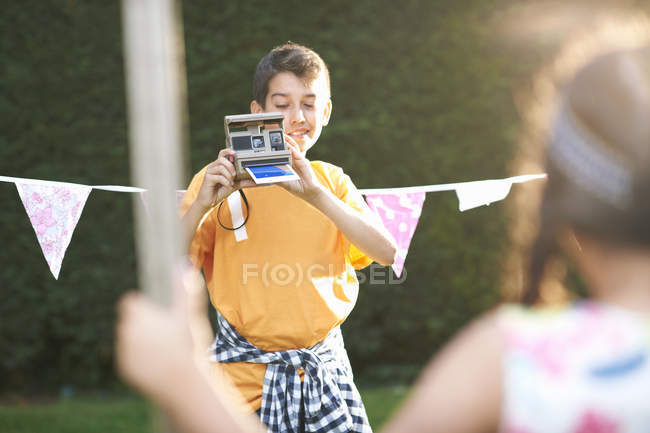 Boy photographing girl using instant camera — Stock Photo