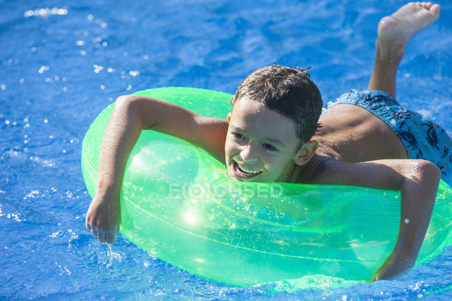 Garçon couché sur anneau gonflable dans la piscine du jardin — Photo de stock