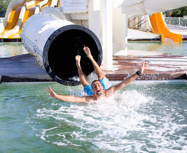 Молодий чоловік падає в басейн зі слайду — стокове фото