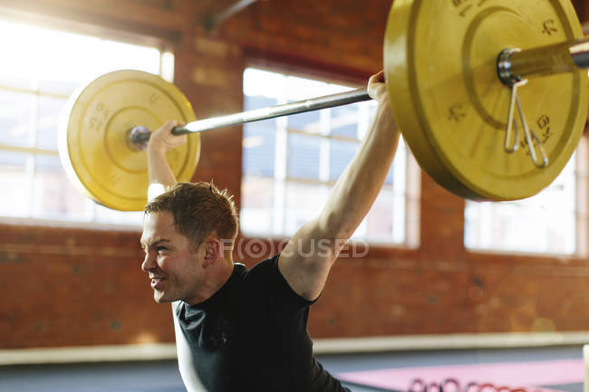 Man lifting weights in gymnasium — Stock Photo