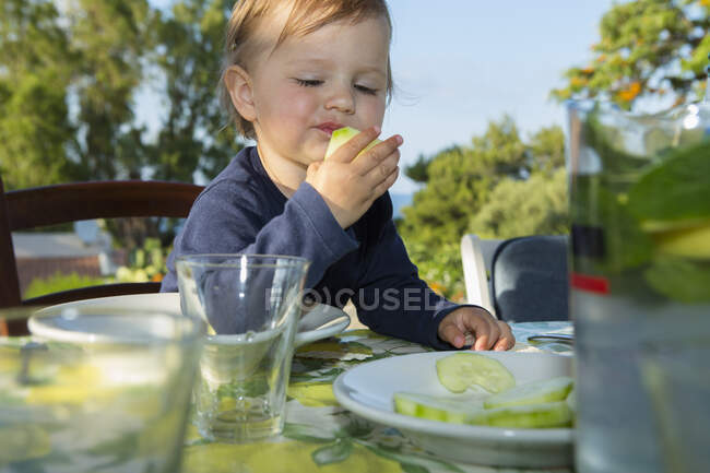Самка малыша ест за столом на открытом воздухе — стоковое фото