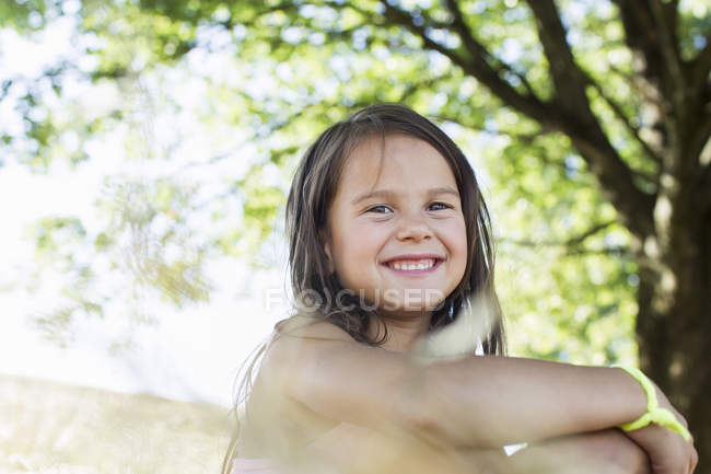 Портрет улыбающейся девушки, сидящей в парке — стоковое фото