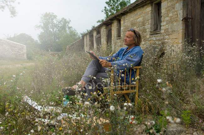 Mann sitzt Skizze vor landwirtschaftlichen Gebäuden — Stockfoto