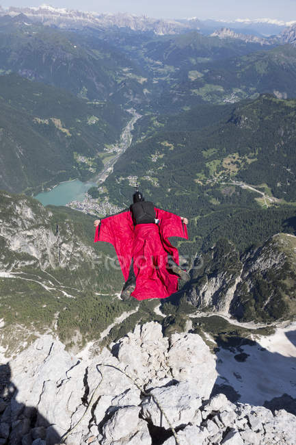 Hombre maduro BASE saltando desde la montaña, Alleghe, Dolomitas, Italia - foto de stock